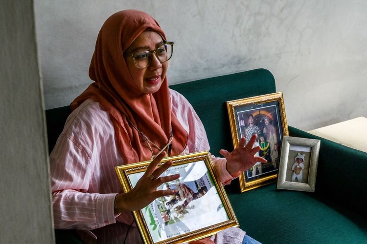This picture taken on February 11, 2023 shows Safitri Puspa Rani holding a picture frame bearing the image of her late son Panghegar Bhumi as she cries while explaining her son's condition before he died, in Jakarta. Bhumi died from fatal acute kidney injury -- days after a doctor prescribed him cough syrup that has been linked to more than 200 child deaths in Indonesia, according to the country's health ministry.