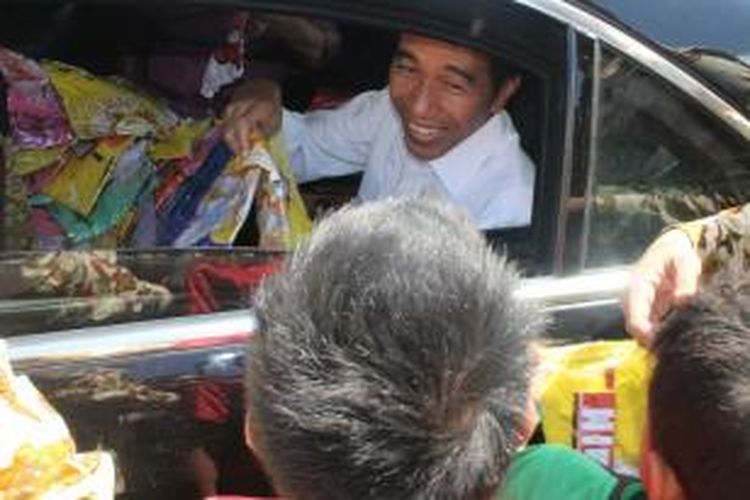 Presiden Jokowi sedang membagikan kaos dan buku kepada anak-anak di dekat bendungan Raknamo, Kabupaten Kupang, Nusa Tenggara Timur (NTT), Sabtu (25/7/2015)