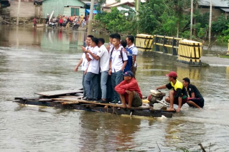 Siswa SMA 14 Ranomeeto Barat, Kabupaten Konawe Selatan, Sultra, terpaksa mengunakan rakit darurat untuk sampai ke sekolah karena jalan putus akibat banjir. 