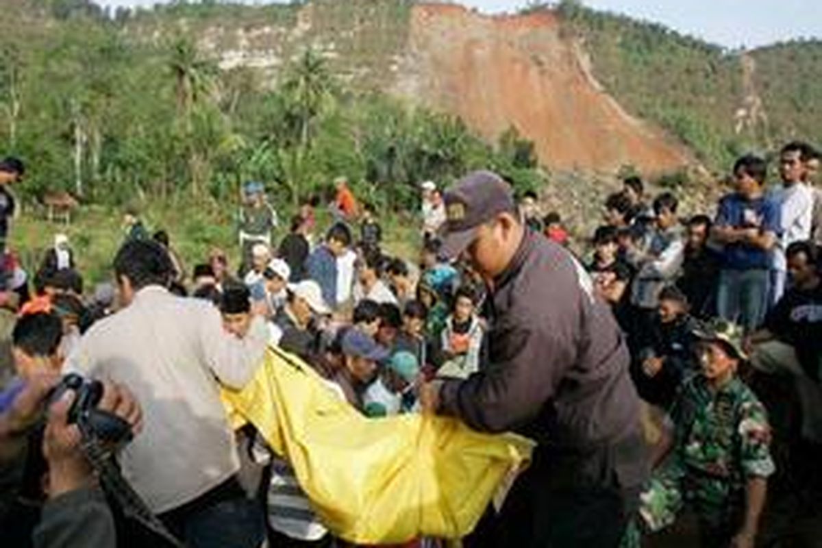 Polisi mengevakuasi korban tewas tertimpa longsor akibat gempa di Desa Cikangkareng, Cibinong, Kabupaten Cianjur, Kamis (3/9).