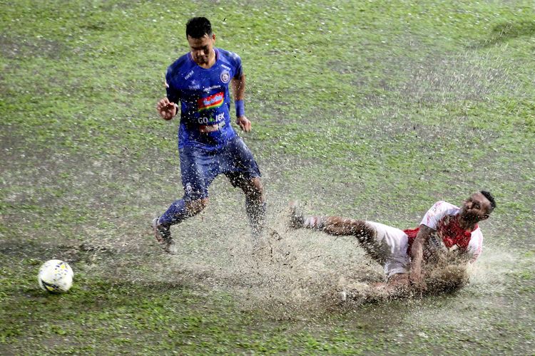 Pemain Arema FC M Rafli (kanan) berebut bola dengan pemain Persipura Jayapura Titus Bonai (terjatuh) pada Pekan 7 Liga 12019 yang berakhir dengan skor 3-1 di Stadion Gajayana Malang, Jawa Timur, Kamis (04/07/2019) sore.