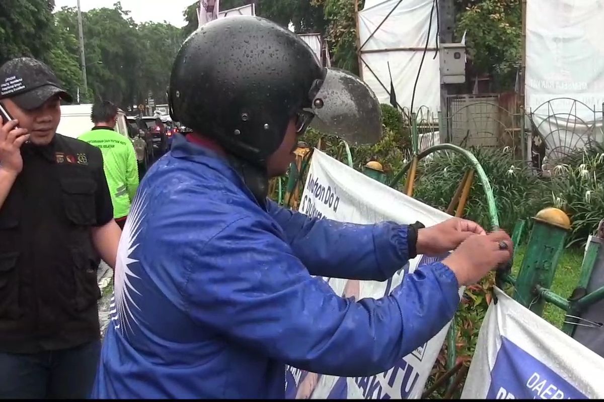 Perwakilan Partai Amanat Nasional (PAN) saat mencabut alat peraga kampanye (APK) dari pagar yang ambruk di Taman Ampera, Pasar Minggu, Jakarta Selatan, Jumat (19/1/2024).
