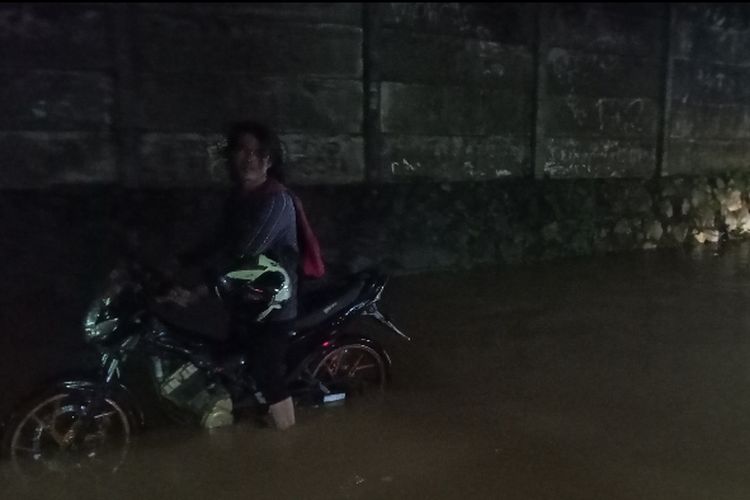 Salah seorang pengendara terpaksa menggiring motornya yang mogok saat melewati Jalanan di Gang Toha, RT 02 RW 02 Kelurahan Rawa Buntu, Kecamatan Serpong, Tangerang Selatan pada Jumat (23/9/2022) malam. Foto diambil pukul 19.23 WIB di lokasi.