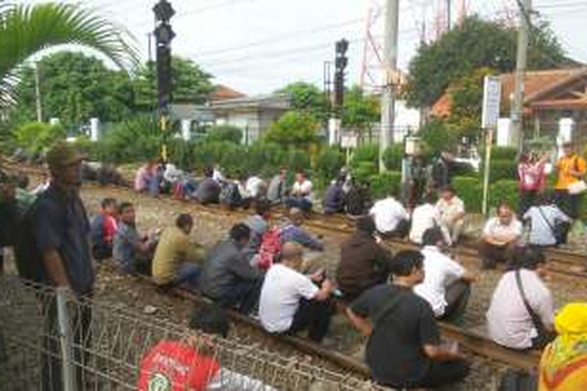 Para calon penumpang KRL commuter line di Stasiun Depok duduk di atas tangga peron akibat rangkaian KRL yang tersedia tak kunjung diberangkatkan, Rabu (3/2/2016).