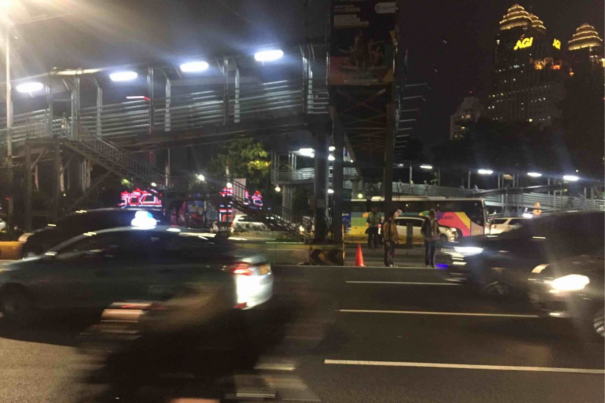 Sejumlah warga  bertaruh nyawa saat berusaha menyeberang jalan usai turun dari Jembatan Penyeberangan Orang (JPO)  Polda di Jalan Jenderal Sudirman, Jakarta Pusat, Senin (13/8/2018) malam. Pasalnya, tak ada pengamanan terhadap warga yang ingin menyeberang jalan menuju Jalan Jenderal Sudirman setelah turun dari JPO tersebut.