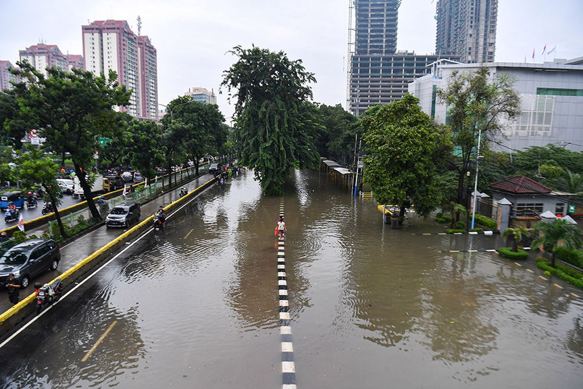 Warga berjalan melintasi banjir di Jalan Letjen Suprapto, Jakarta Pusat, Sabtu (8/2/2020). Hujan deras yang mengguyur Jakarta sejak Sabtu (8/2) dini hari membuat sejumlah kawasan di Ibu Kota terendam banjir.