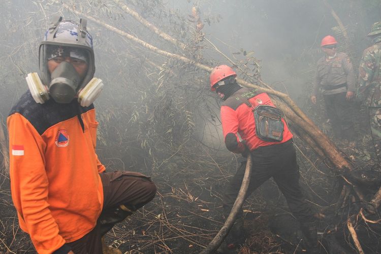 Satgas Karhutla Riau melakukan pemadaman kebakaran lahan gambut di Desa Rimbo Panjang, Kabupaten Kampar, Riau, Senin (16/9/2019). Kebakaran hutan dan lahan (karhutla) yang masih terjadi membuat sejumlah wilayah di Provinsi Riau terpapar kabut asap. ANTARA FOTO/Rony Muharrman/ama.