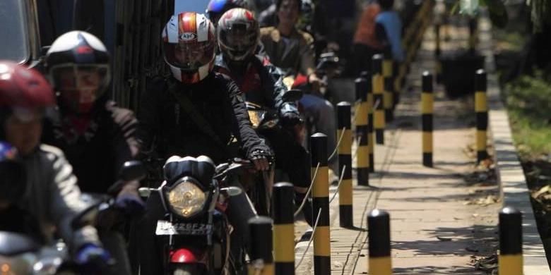 Pengguna sepeda motor tersendat di samping trotoar yang dipasangi tiang besi dan kawat baja di Jalan Raya Bekasi, Cakung, Jakarta Timur, Senin (16/4/2012). Tiang besi dan kawat baja dipasang untuk menutup jalan ke trotoar yang sering dipakai pengguna sepeda motor saat macet.
