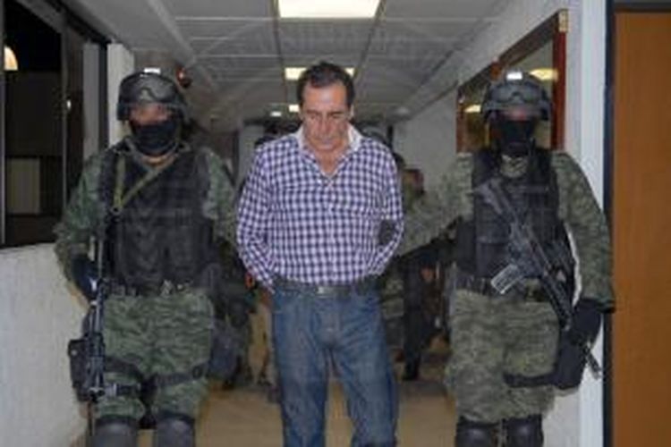 Dua orang anggota marinir Meksiko menggiring gembong narkoba Hector Beltran Leyva yang ditangkap di sebuah kota wisata.
