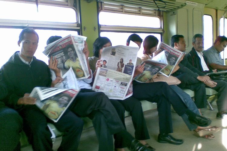Potret penumpang KA PRameks yang tengah membaca koran di tengah perjalanan kereta