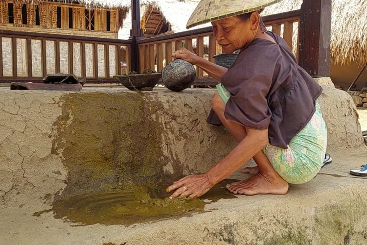 Salah seorang warga Sasak Ende ketika melulurkan campuran kotoran sapi ke sebuah saung di Desa Wisata Sasak Ende, Sengkol, Pujut, Kabupaten Lombok Tengah, Selasa (6/12/2022).