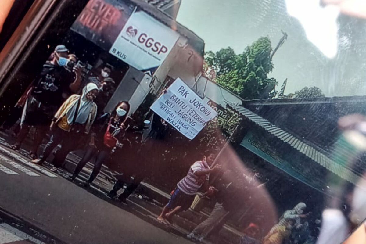 Seorang pria membentangkan poster di depan mobil Presiden Jokowi di Kota Blitar, Selasa (7/9/2021)