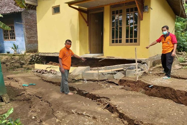 Petugas BPBD Kabupaten Purworejo menunjukkan rekahan tanah akibat fenomena tanah bergerak di Desa Tegalsari, Kecamatan Bruno, Kabupaten Purworejo, Senin (16/1/2021).