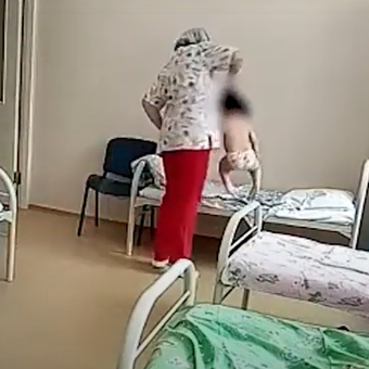 Seorang perawat menjambak rambut balita untuk menaikkan bocah itu ke atas kasur.