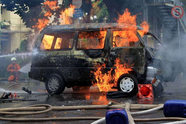 Petugas berusaha memadamkan mobil Daihatsu Zebra B2791AJ yang terbakar di Jalan Trunojoyo, samping Mabes Polri, Kebayoran Baru, Jakarta, Rabu (4/2/2015). Mobil itu membawa lima tangki berisi ratusan liter bahan bakar minyak.  KOMPAS IMAGES/KRISTIANTO PURNOMO
