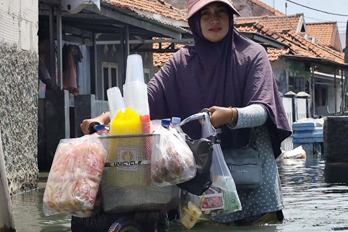 Warga saat menerobos banjir rob setinggi 1 meter lebih di Desa Eretan Wetan, Kecamatan Kandanghaur, Kabupaten Indramayu, Jawa Barat, Selasa (7/10/2025)