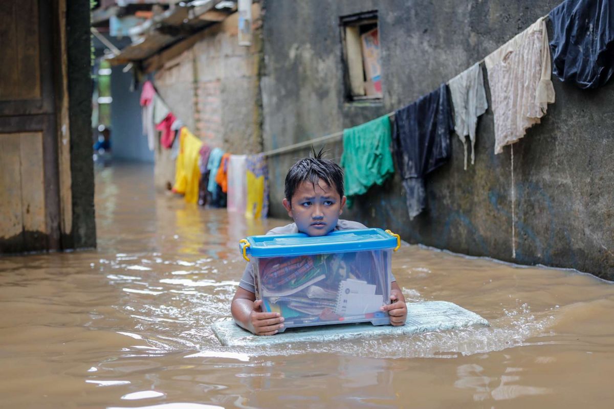 Warga mengungsi sambil membawa barang-barang berharga saat terjadi banjir di Rawajati, Pancoran, Jakarta Selatan, Senin (5/2/2018). Sebanyak 263 keluarga di Rawajati RW 007, RT 002, RT 003, RT 004, dan RT 005 dilaporkan terdampak banjir akibat luapan Sungai Ciliwung.