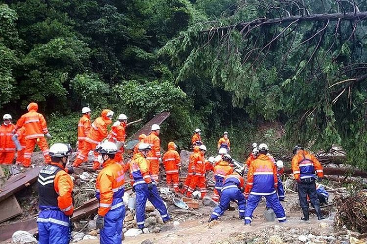 Pemadam kebakaran tengah bekerja untuk melakukan evakuasi pada dua rumah yang hancur akibat tertimpa tanah longsor. Lokasi kejadian di Unzen, prefektur Nagasaki, Jepang. 