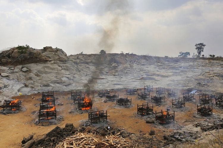 Tumpukan kayu pemakaman dua puluh lima korban COVID-19 dibakar di krematorium terbuka yang didirikan di tambang granit di pinggiran Bengaluru, India, Rabu (5/5/2021).