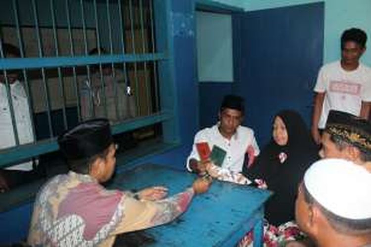 LS (kemeja putih) dan RNS (jilbab hitam) memperlihatkan buku pernikahan usai ijab kabul di ruang tunggu tahanan Polres Kota Baubau, Kamis (15/12/2016). 