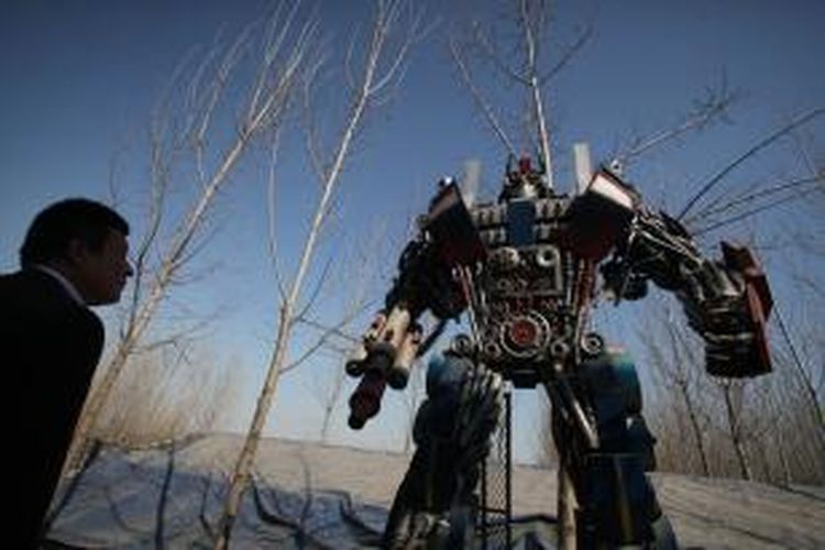 Seorang pria sedang memandangi robot Optimus Prime, salah satu karakter dalam film Transformers, yang dibuat para petani China dengan bahan onderdil mobil bekas.