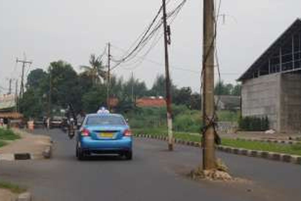 Sebanyak empat tiang listrik berdiri di tengah Jalan Raya Ciater, Tangerang Selatan, Selasa (31/5/2016). Keberadaan tiang listrik di tengah jalan ini kerap membuat pengendara terlibat kecelakaan di daerah tersebut. 