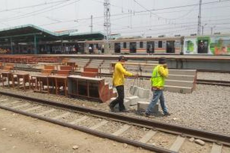 Dua orang pekerja terlihat sedang membawa sebuah beton dalam proyek pengerjaan perpanjangan peron di Stasiun Manggarai, Sabtu (12/9/2015). Perpanjangan peron dilakukan terkait akan segera dioperasikannya kereta rel listrik commuterline drngan formasi 12 kereta.