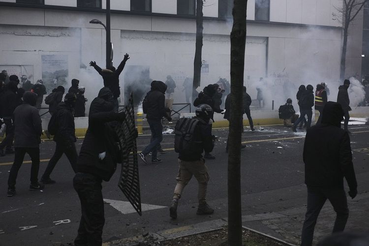 Para pemuda berjalan melewati gas air mata selama demonstrasi pada Sabtu (5/12/2020) di Paris, Perancis. Ribuan orang turun ke jalan menentang RUU keamanan. Ketegangan dengan cepat meningkat di Paris ketika penyusup membakar beberapa mobil, memecahkan jendela, dan melemparkan benda-benda ke arah polisi.