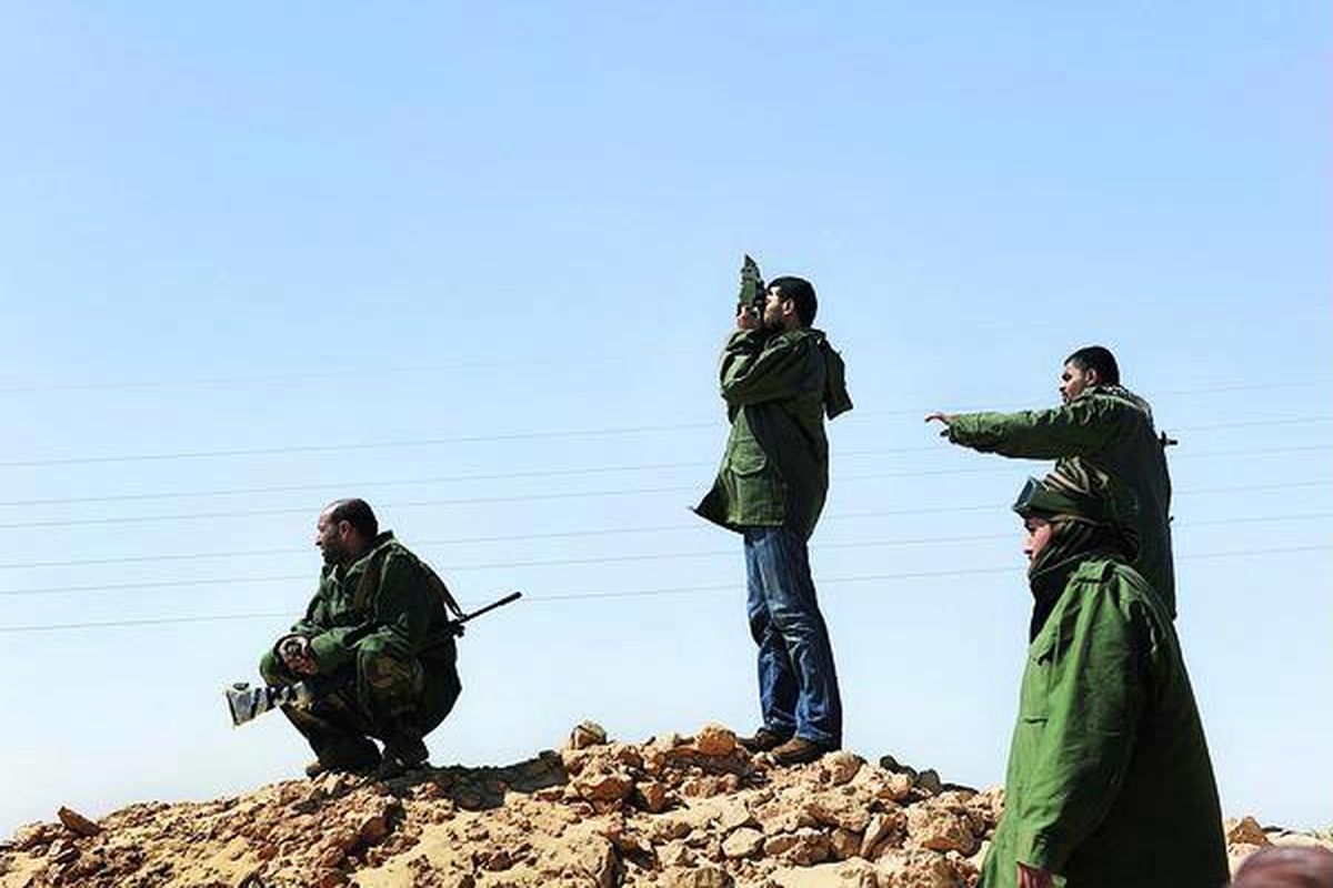 Anggota pasukan oposisi mengamati pasukan Moammar Khadafy dari ketinggian sebuah bukit di dekat kota penting, Ajdabiya, Libya, Rabu (23/3), pada saat pasukan Pemerintah Libya mengurung kota tersebut. 