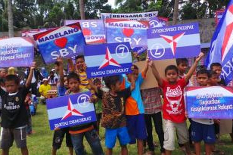 Anak-anak kecil tampak membawa atribut kampanye Partai Demokrat di Magelang, Jumat (14/3/2014).