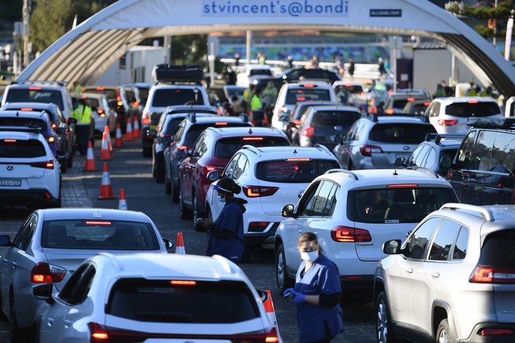 Orang-orang mengantre di dalam mobil untuk melakukan tes Covid-19 di klinik pop-up Pantai Bondi, Sydney, Australia, 25 Juni 2021. Sebagian Sydney akan lockdown mulai tengah malam hari itu, akibat lonjakan kasus virus corona di kota terbesar Australia tersebut.