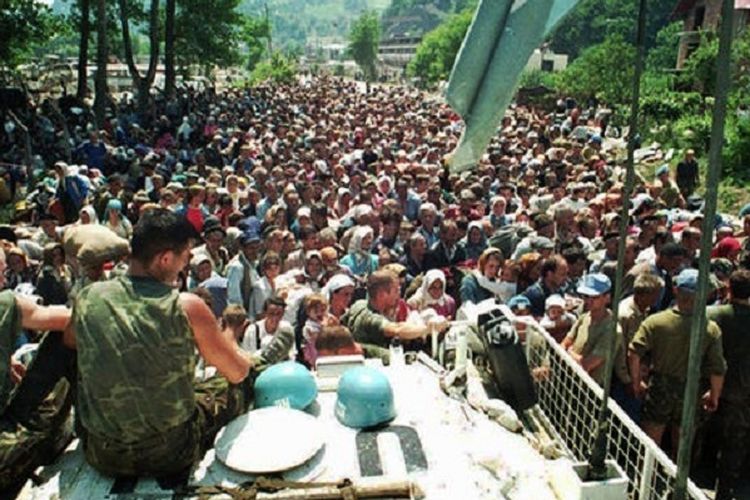 Pasukan penjaga perdamaian PBB asal Belanda duduk santai di atas sebuah kendaraan lapis baja saat para pengungsi Muslim dari Srebrenica berkumpul di desa Potocari, dekat markas tentara Belanda, Juli 1995. 