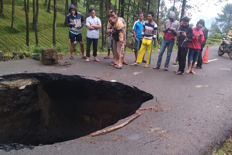 Warga melihat lubang besar di ruas jalan provinsi Brebes-Tegal tepatnya di jalan Desa Batursari Kecamatan Sirampog, Kabupaten Brebes, Jawa Tengah, Sabtu (13/2/2021). (Istimewa)