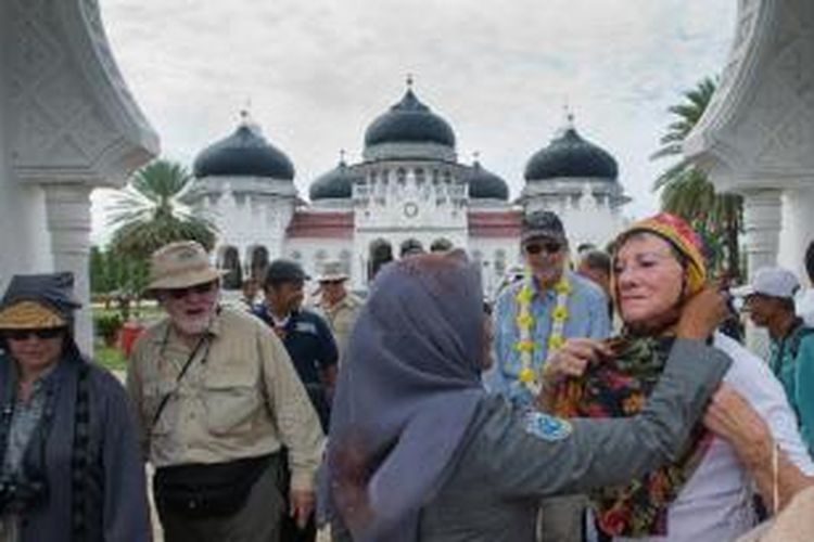 Turis dari kapal pesiar MV Clipper Odyssey mengenakan pakaian khusus saat memasuki kompleks Masjid Raya Baiturrahman, Banda Aceh, Kamis (10/1/2013). Kapal yang mengangkut 150 penumpang dari berbagai negara dalam tour wisata Zegrahm Expedition tersebut melego jangkar selama enam jam di lepas pantai Banda Aceh untuk membawa para turis melakukan city tour ke beberapa situs sejarah dan tsunami Aceh. 