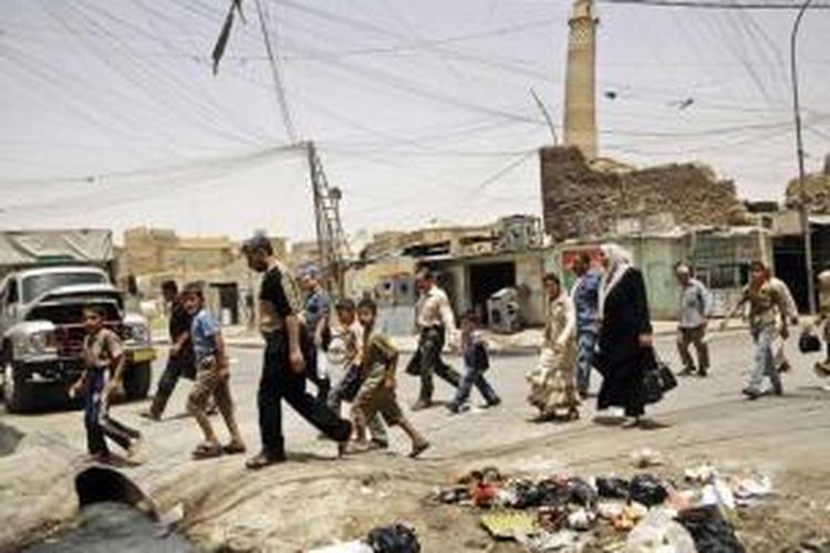 Warga berjalan melewati menara masjid yang miring di daerah pasar yang ramai di Mosul, Irak. Militan negara Islam telah mengancam untuk menghancurkan Mosul yang telah berusia 850 tahun.