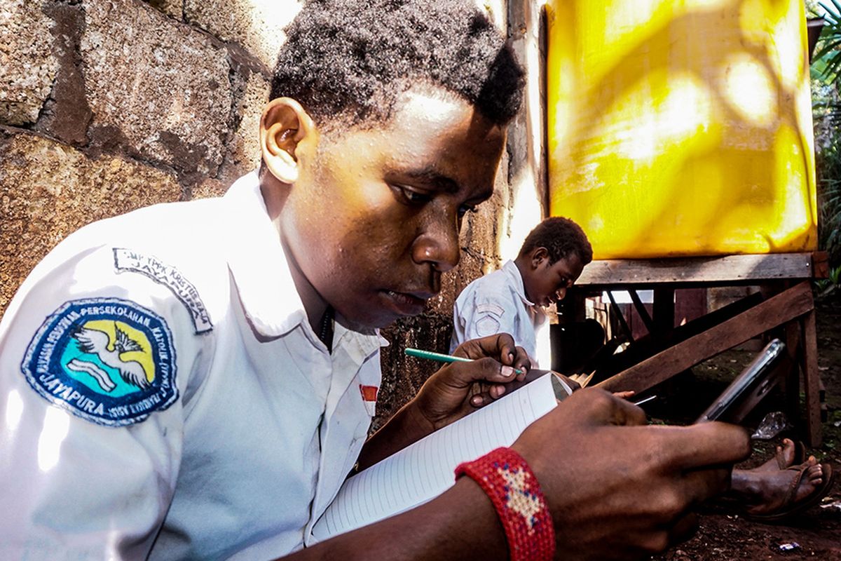 Yonas Kedeikoto (15) (kiri) dan Jekson Pigome (12) mengikuti proses belajar mengajar secara daring di Kota Jayapura, Papua, Senin (10/8/2020). Dua pelajar kelas IX dan VIII SMP Yayasan Pembinaan Pendidikan Kristen (YPPK) Kristus Raja Jayapura tersebut mengaku mulai hari ini wajib mengenakan seragam sekolah saat mengikuti pelajaran daring.