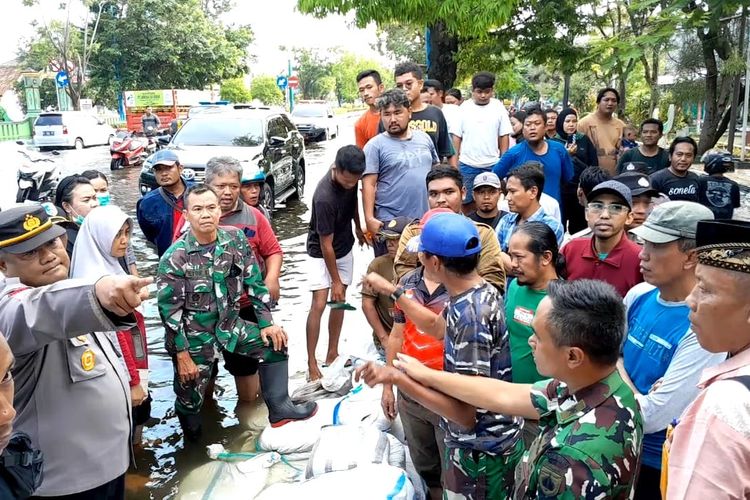 Antar warga sempat bersitegang saat diminta membongkar tanggul sak di tepi Jalan Sultan Fatah depan Kampung Bogorame, Kelurahan Mangunjiwan, Kecamatan Demak, Selasa (19/3/2024). (KOMPAS.COM/NUR ZAIDI)