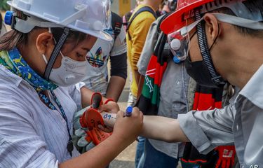 An anti-coup protester writes emergency information of another protester on his arm in Yangon, Myanmar, (3/3/2021)
