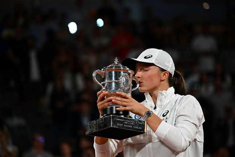 Petenis Polandia, Iga Swiatek, mencium trofi usai juara French Open 2022. Dalam laga final di Court Philippe-Chatrier, Paris, Sabtu (4/6/2022), Swiatek mengalahkan petenis Amerika Serikat, Coco Gauff. Ini gelar kedua Swiatek di Roland Garros.