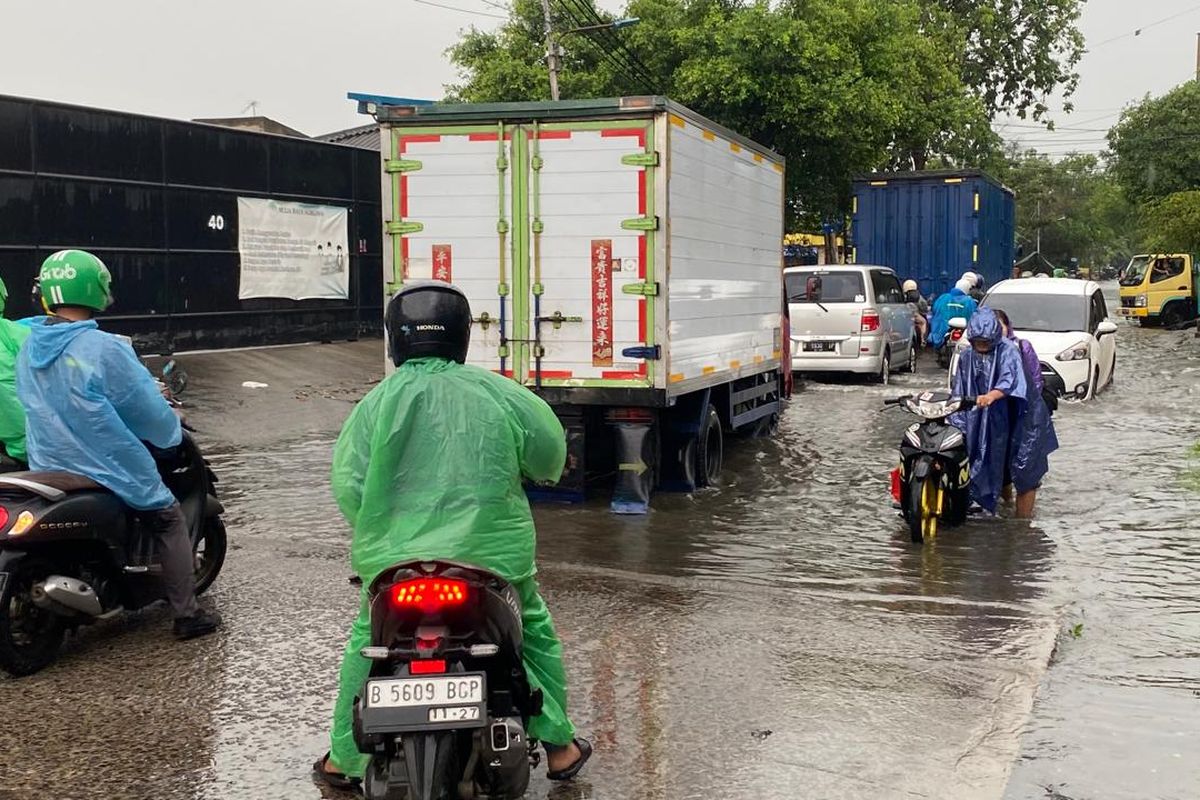 Pengendara sepeda motor mematikan mesin dan mendorong motornya karena banjir di Jalan Kapuk Raya, Cengkareng, Jakarta Barat, Jumat (22/3/2024). 