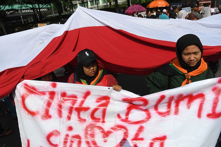 Mahasiswa pecinta alam dari berbagai universitas se-Jabodetabek membawa bendera raksasa ketika melakukan aksi di kasawan Bundaran HI Jakarta, Minggu (21/4/2019). Aksi tersebut dalam rangka peringati Hari Bumi pada 22 April.