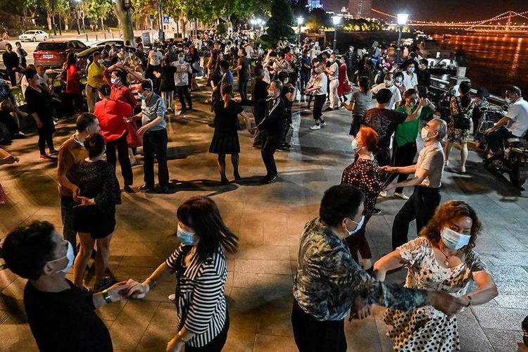 Sejumlah pasangan dengan mengenakan masker menari di sebuah taman di sebelah Sungai Yangtze, Wuhan, Provinsi Hubei, China, Selasa (12/5/2020). Memasuki enam pekan bebas dari lockdown yang diterapkan akibat pandemi Covid-19 sejak Januari lalu, warga Wuhan kembali beraktivitas walau dalam kondisi terbatas.