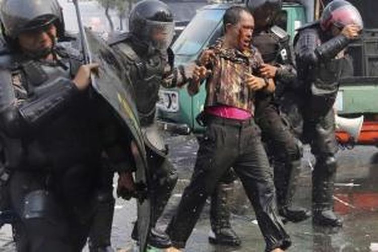 Polisi mengamankan demonstran pendukung Prabowo-Hatta yang terluka saat unjuk rasa yang berakhir ricuh di Jalan Medan Merdeka Barat, Jakarta, Kamis (21/8/2014). Bentrokan dengan polisi terjadi saat massa berusaha menembus barikade polisi agar bisa mendekat ke gedung Mahkamah Konsistusi.