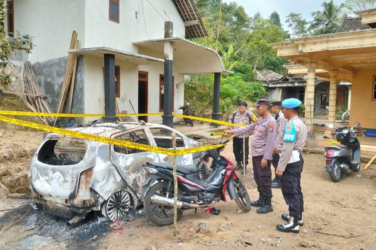 Polisi di lokasi kejadian. Mobil kepala Desa Wonokerto Kecamatan Suruh Kabupaten Trenggalek Jawa Timur, dibakar warganya yang diduga ODGJ, Senin (18/08/2025).
