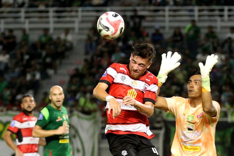 Penjaga gawang Persebaya Surabaya Andhika Ramadhani berduel dengan pemain Madura United Jordy Wehrmann saat laga pekan ke-28 Super League 2025-2026 yang berakhir dengan skor 1-2 di Stadion Gelora Bung Tomo Surabaya, Jawa Timur, Jumat (17/4/2026) malam.