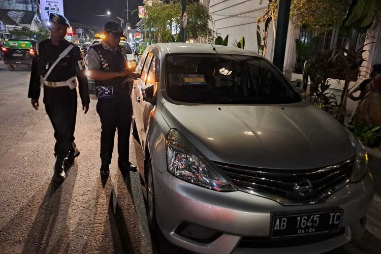 Petugas Dishub saat menempel stiker pelanggaran di Jalan Sarkem, Kota Yogyakarta, Rabu (27/12/2023)