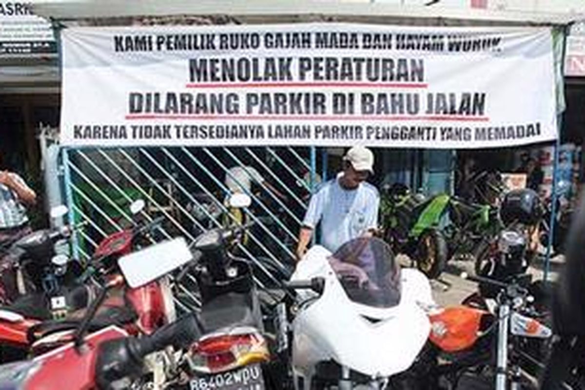 Tukang parkir di Jalan Gajah Mada, Jakarta Pusat, Adhi, menata sepeda motor yang diparkir di trotoar, Selasa (21/6/2011). Sejumlah pemilik toko dan tukang parkir di kawasan tersebut menolak kebijakan larangan parkir di ruas Jalan Hayam Wuruk dan Jalan Gajah Mada.