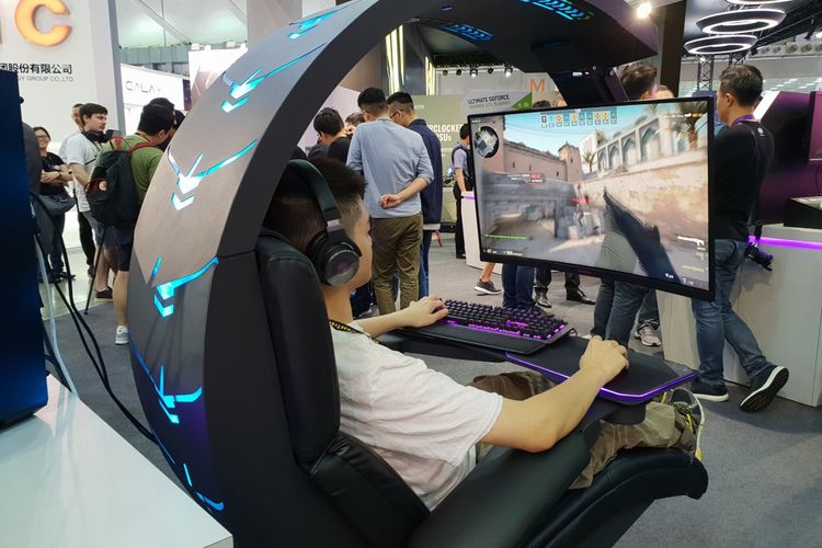 Seorang pengunjung mencoba bermain game FPS di sebuah stand. 