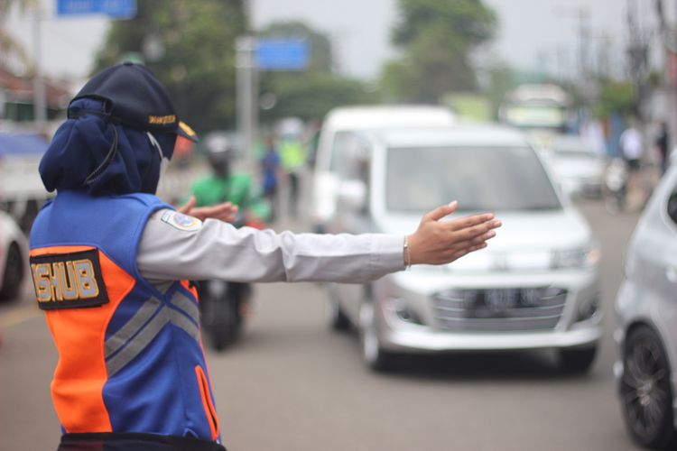 Seorang petugas tengah mengatur lalu lintas kendaraan di kawasan tugu Lampu Gentur Cianjur, Jawa Barat, pada momen mudik lebaran 2022.