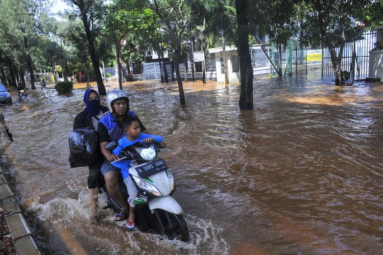 Pengendara motor menerobos banjir di Pulomas, Jakarta Timur, Minggu (23/2/2020). Curah hujan yang tinggi dan kualitas drainase yang buruk membuat daerah tersebut terendam banjir. ANTARA FOTO/ Fakhri Hermansyah/foc.